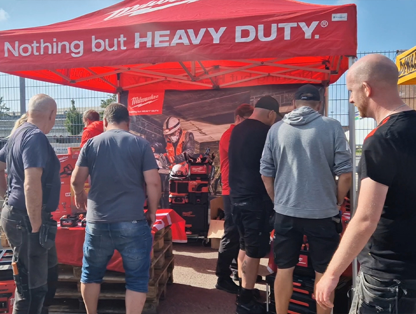 bilder på människor som är på ett event vid en leverantörs tält