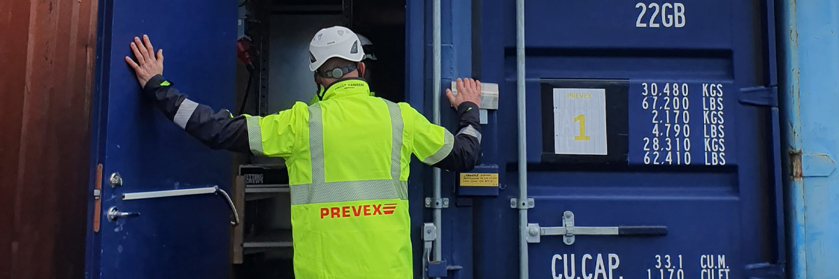 man i arbetskläder som öppnar dörrar till en container