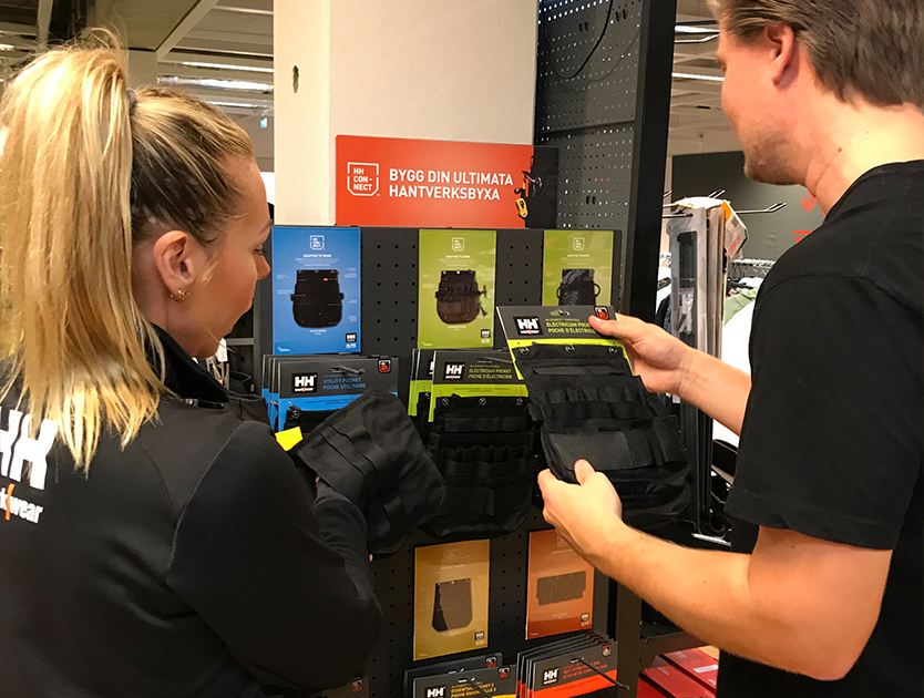två människor som står och tittar på en produkt från helly hansen